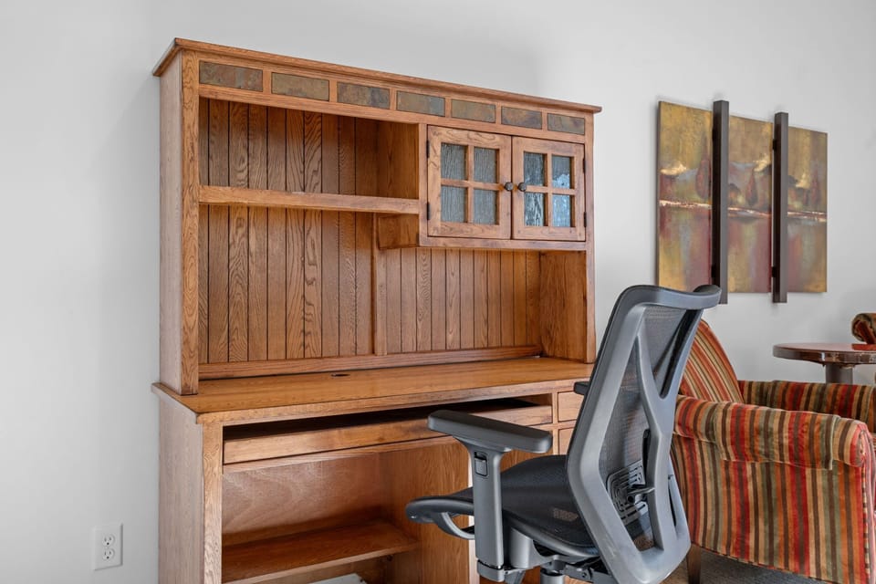 Your dedicated workspace awaits with handcrafted oak hutch, ergonomic chair, and inspiring artwork—perfect for remote work or planning adventures.