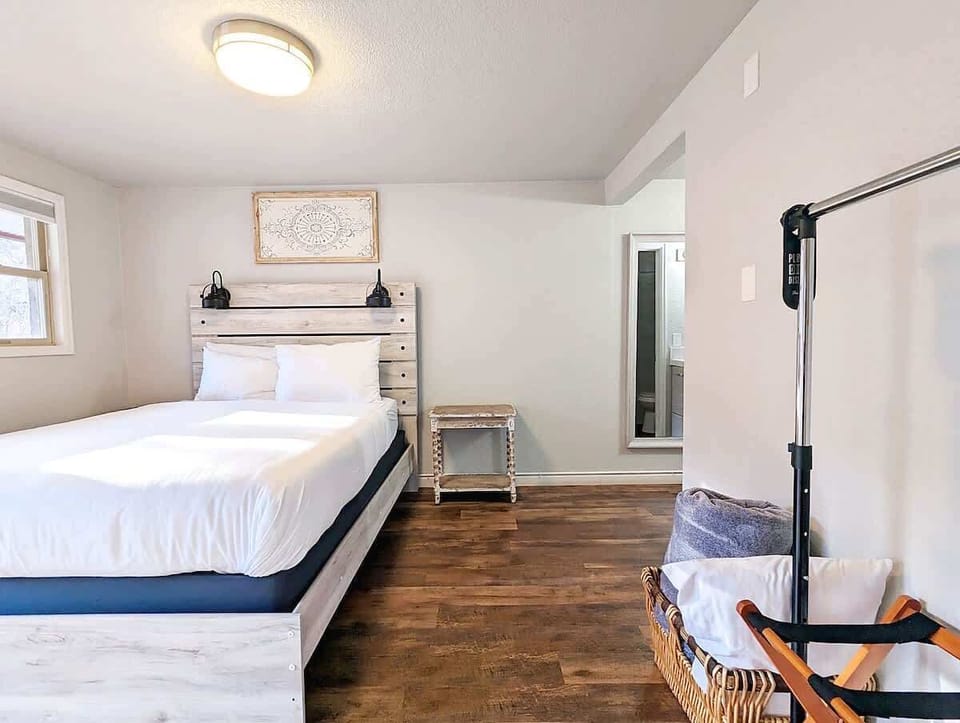 Bedroom view with clean white bedding, soft light, and storage nearby.
