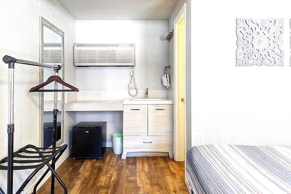 The vanity, mini fridge, and storage area add useful apartment-style function to the room.

