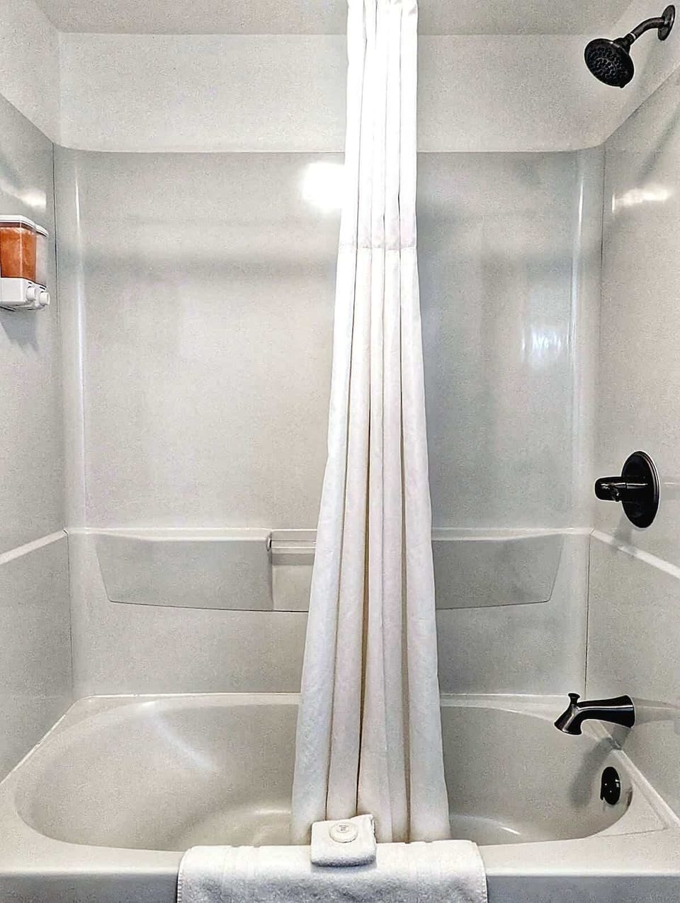 Tub-shower combination with clean white finishes and simple towel styling