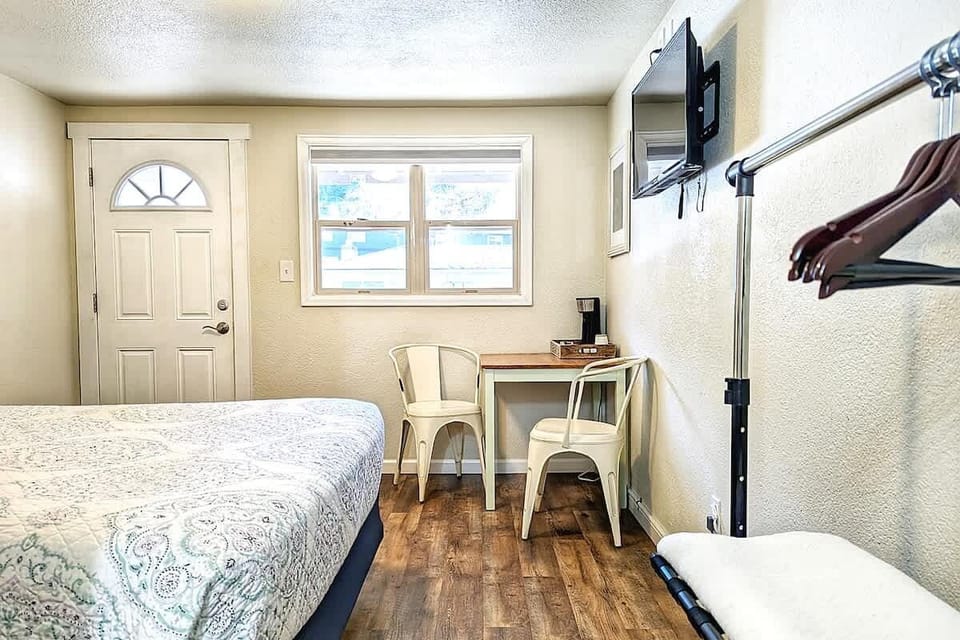  A clear look at the room layout, with the bed, small table, TV, and hanging space all in view.
