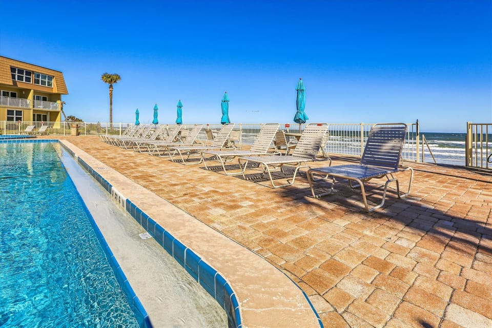 Poolside seating with umbrellas overlooking the ocean.
