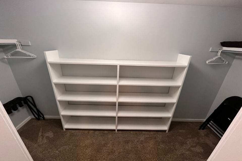 Large closet in king bedroom with extra towels, blankets, and chairs.