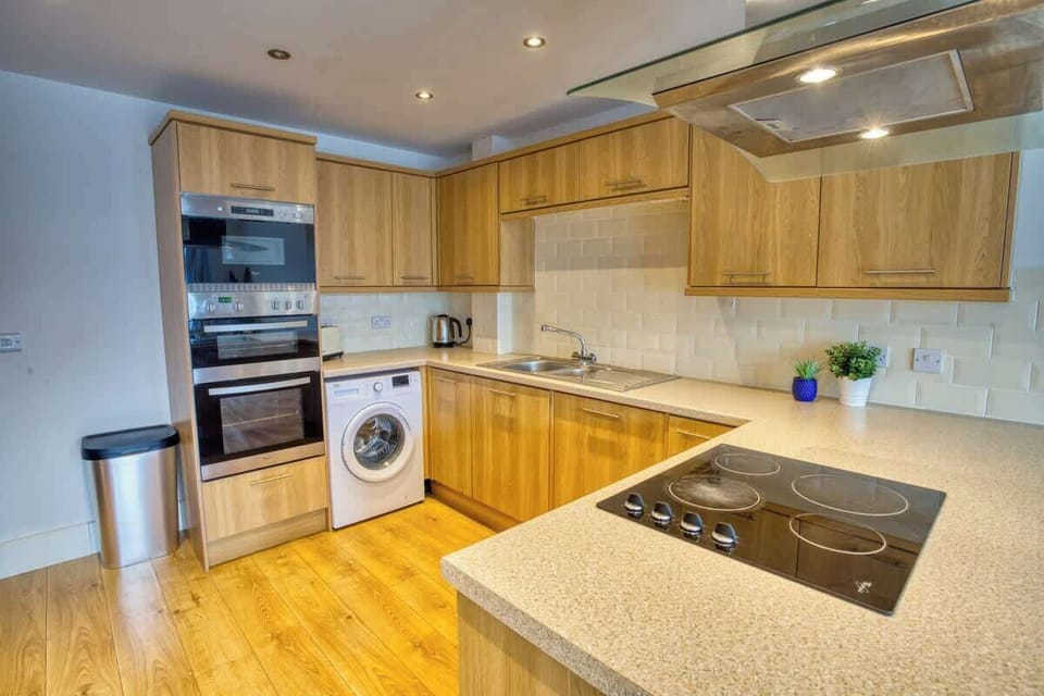 A sleek and spotless kitchen equipped with all essential amenities and a convenient washing machine-where functionality meets modern simplicity for effortless living.