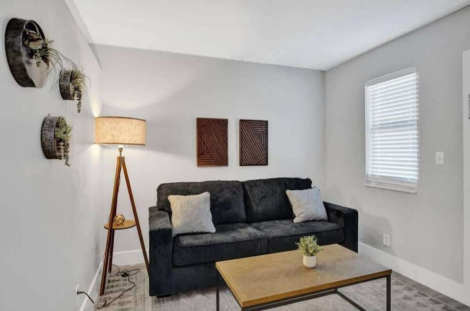 Living room with dark leather sofa, wood coffee table, and natural light from a side window.