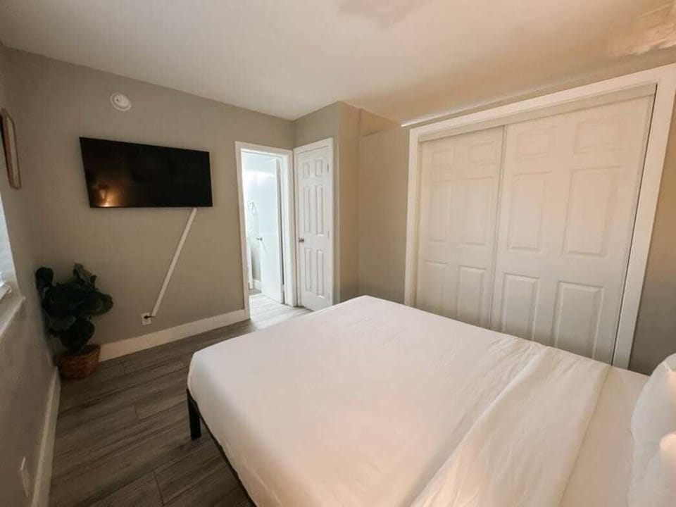 Bedroom with wall-mounted TV and large closet with ample storage.