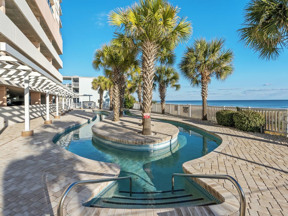 Resort-style beachfront pool with palm trees and sweeping ocean views