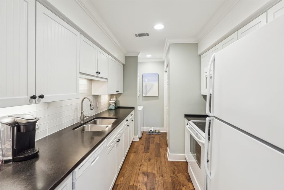 The kitchen boasts plentiful counter space, ideal for preparing family meals, and the convenience of an in-home washer and dryer eliminates the need for external laundry services.