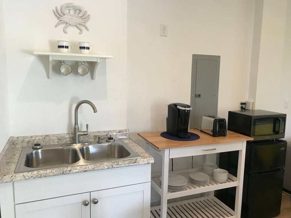 Kitchenette with stocked Keurig, toaster, microwave, refrigerator, freezer, dishes and silverware.