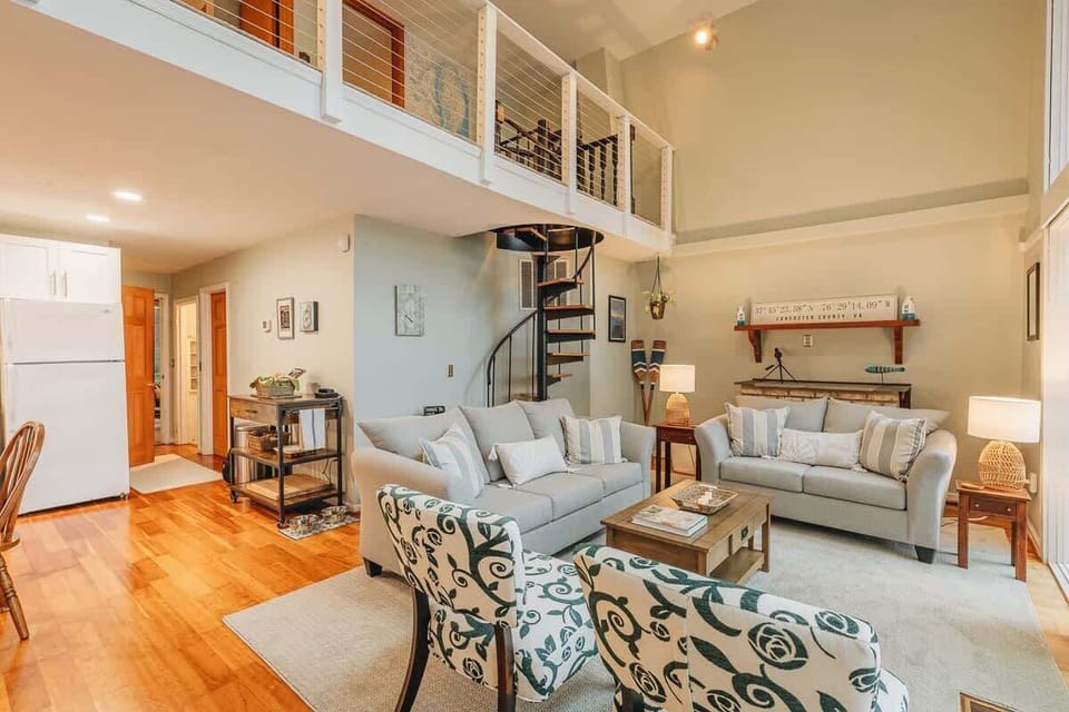 The spiral staircase goes up to the charming loft area with WFH office space and two bedrooms, each with two twin beds. Kitchen off to the right makes it easy to chat and cook at the same time!