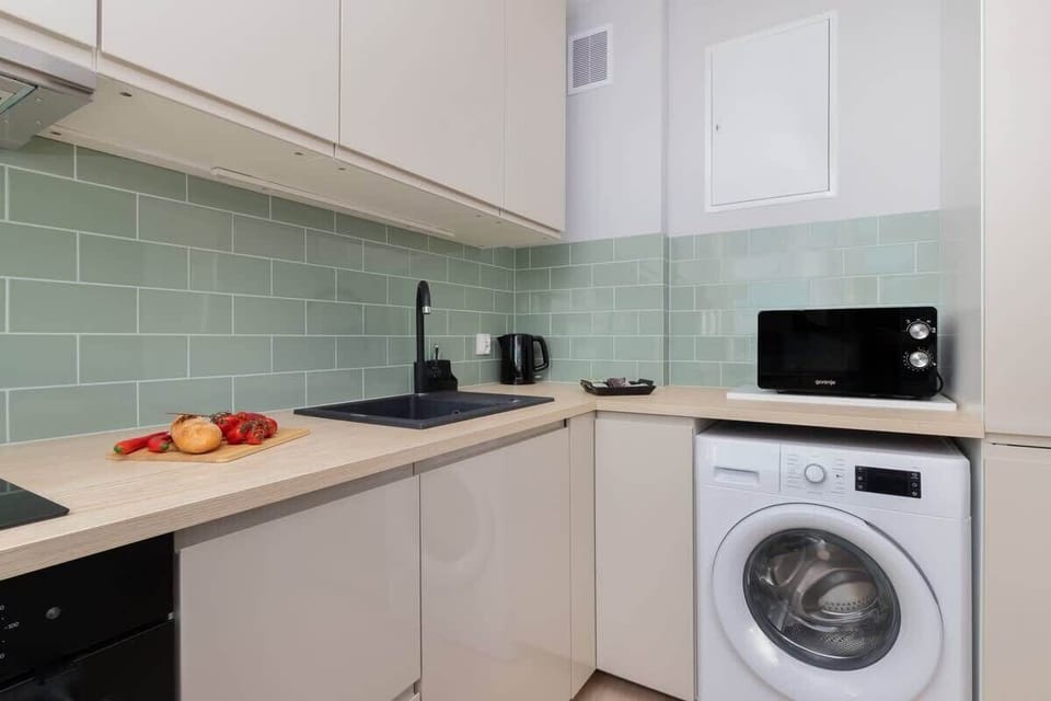 A kitchen angle revealing the light-green subway tile backsplash, white appliances, and a practical layout with ample counter space.

