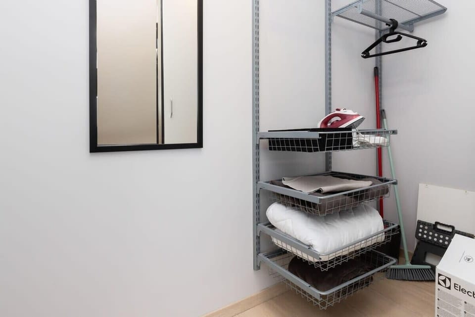 A functional bathroom corner equipped with shelving for towels and an ironing board, maintaining a tidy and organized space.

