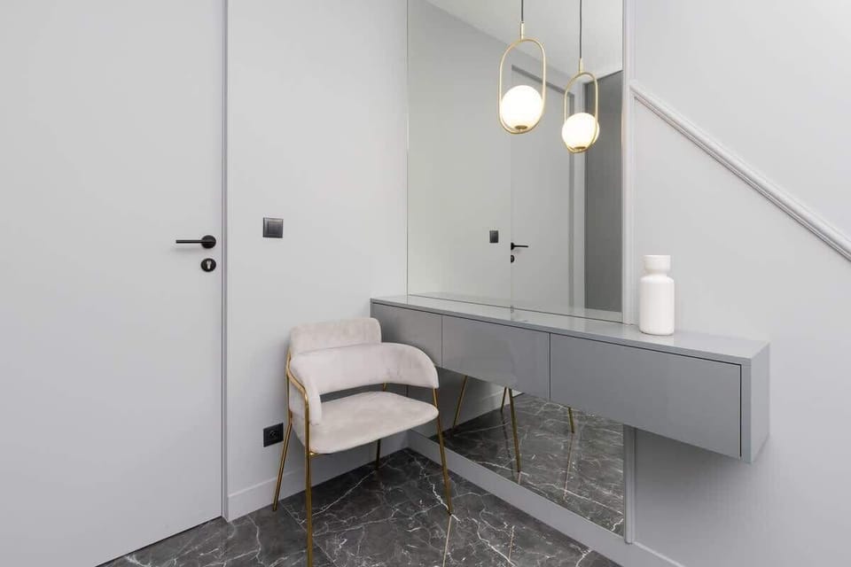 A hallway corner featuring a modern console table, pendant lamps, and a simple door design in keeping with the apartment’s sleek style.







