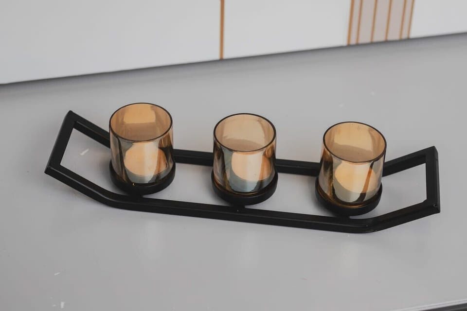 A decorative trio of candles in matte black holders arranged on a sleek grey console for a chic, modern touch.

