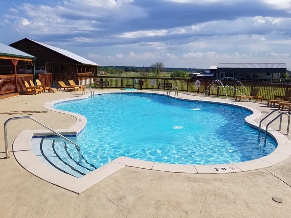 Community pool for guest use with chairs, sun loungers and shaded patio area.