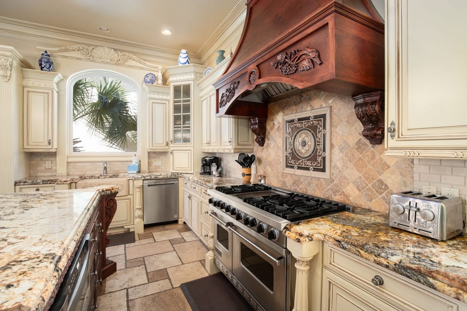 Step into your gourmet kitchen featuring marble countertops, professional appliances, and elegant carved details.