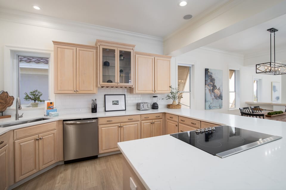 You'll love preparing meals in this spacious kitchen featuring warm wood cabinets, gleaming white countertops, and modern stainless appliances.
