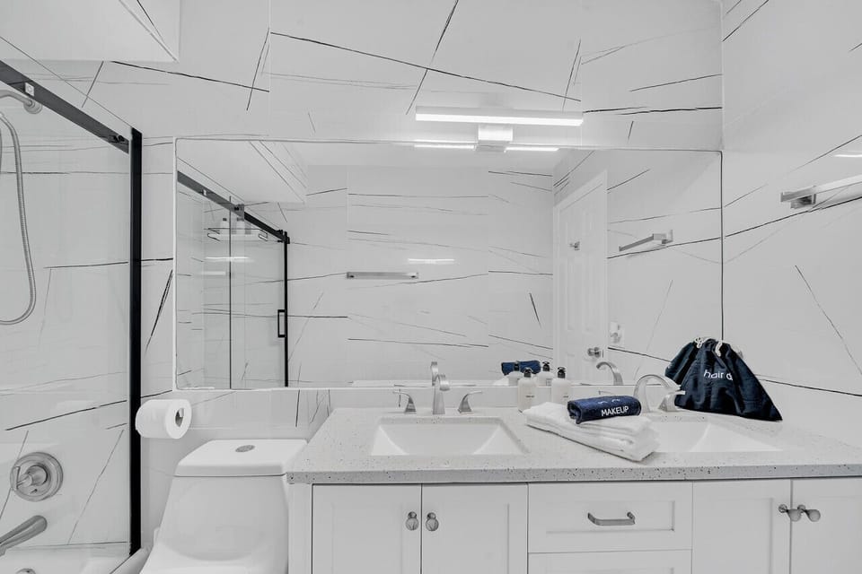 Designer guest bathroom w double vanity, glass shower/tub combo