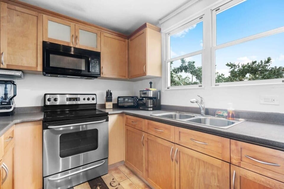 The kitchen is equipped with a fridge, freezer, microwave, stovetop, oven, blender, coffee maker, and toaster oven. It offers seating for three in the kitchen island.