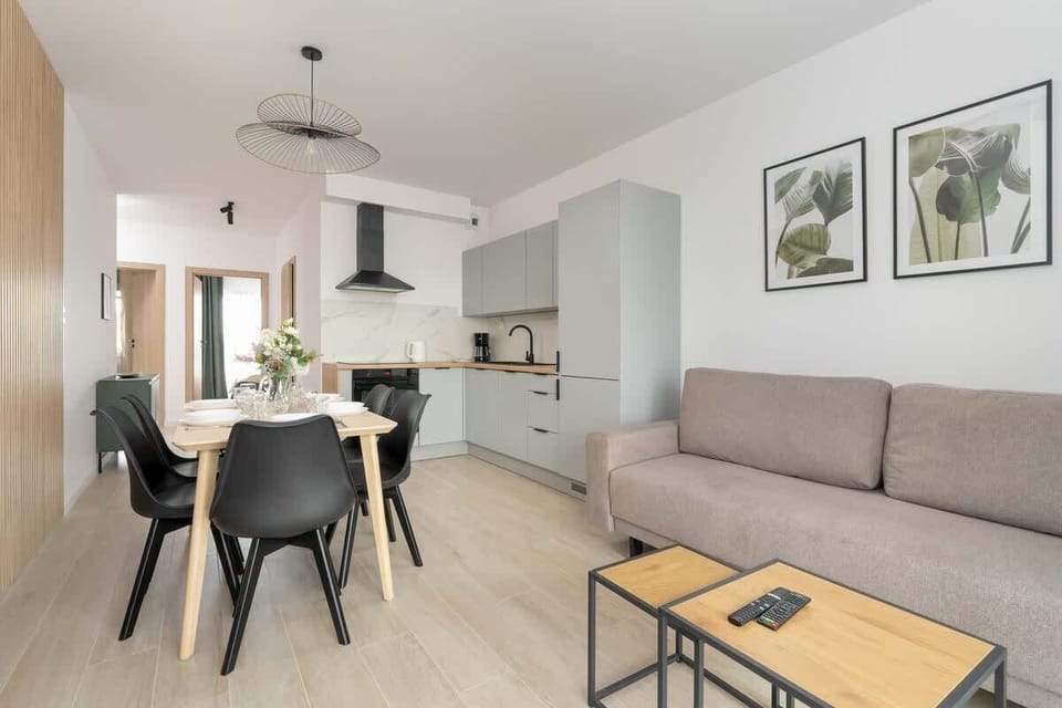An open living and dining space with neutral tones, a comfortable sofa, and framed artwork for a stylish yet cozy atmosphere.

