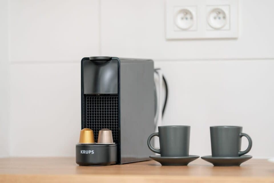 A coffee station featuring a modern coffee machine, black mugs, and a wooden countertop for a cozy morning routine.

