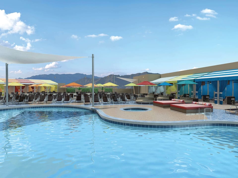 Lounge poolside under bright umbrellas and mountain views.