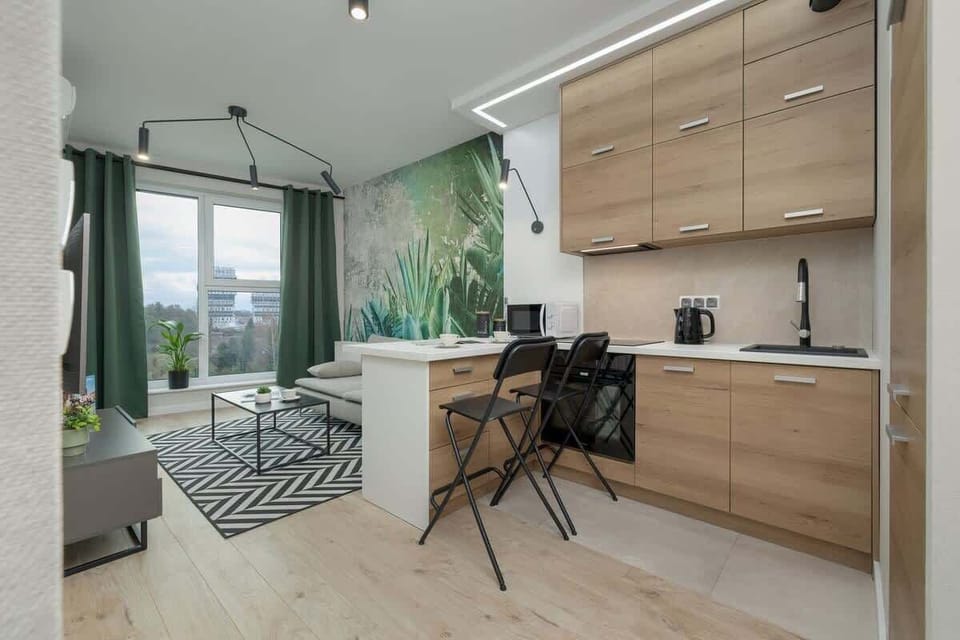 An open-concept space with a compact kitchen, dining table, and the same botanical backdrop, blending natural tones and modern finishes.

