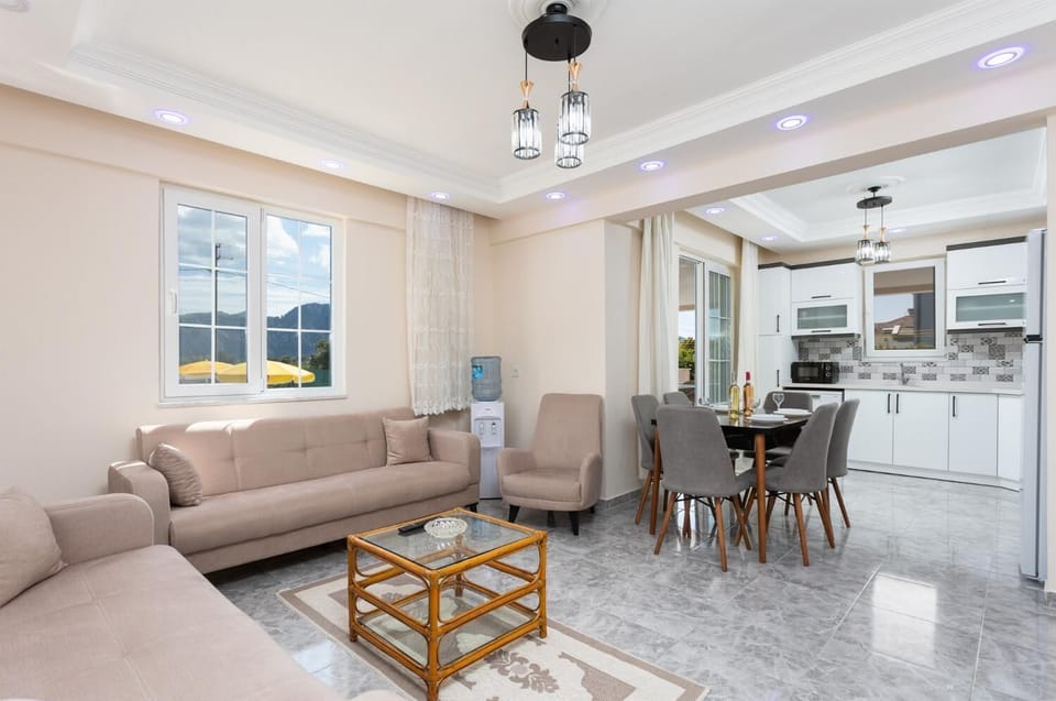 Open-plan living room with sofas, dining area, kitchen, A/C, WiFi internet, and satellite TV