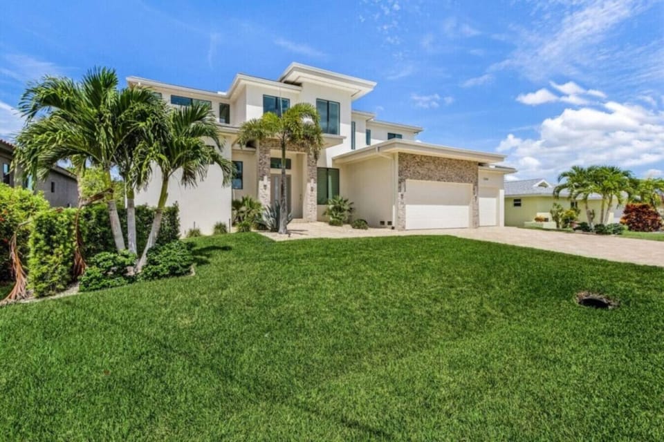 Elegant modern home with lush landscaping and spacious driveway.