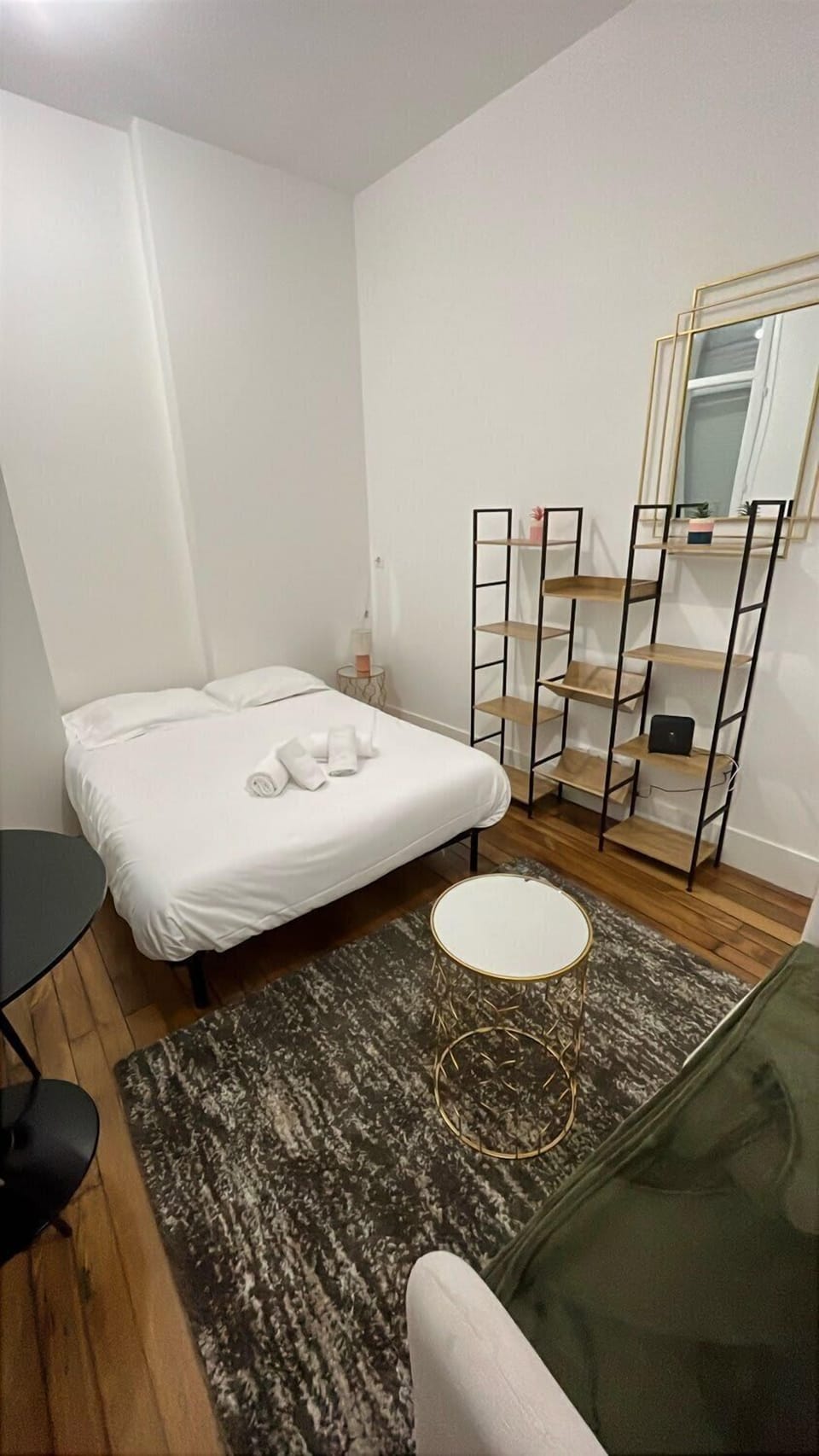 Coin nuit avec lit double, miroir en pied, étagère et tapis — espace chambre du studio Le Chill proche canal du Midi Toulouse