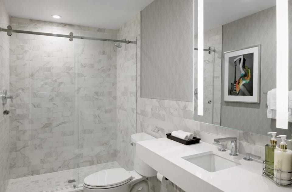 Refresh in a gleaming marble bath with bright vanity lighting.