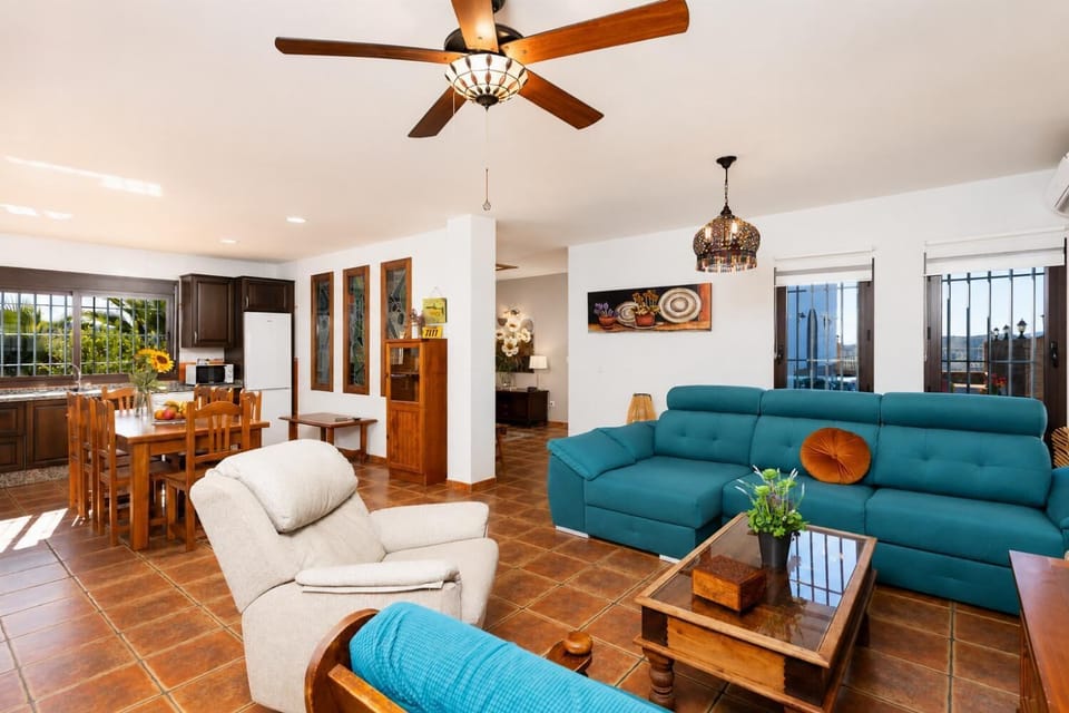 Open-plan living room with sofa, dining area, kitchen, A/C, WiFi internet, and satellite TV
