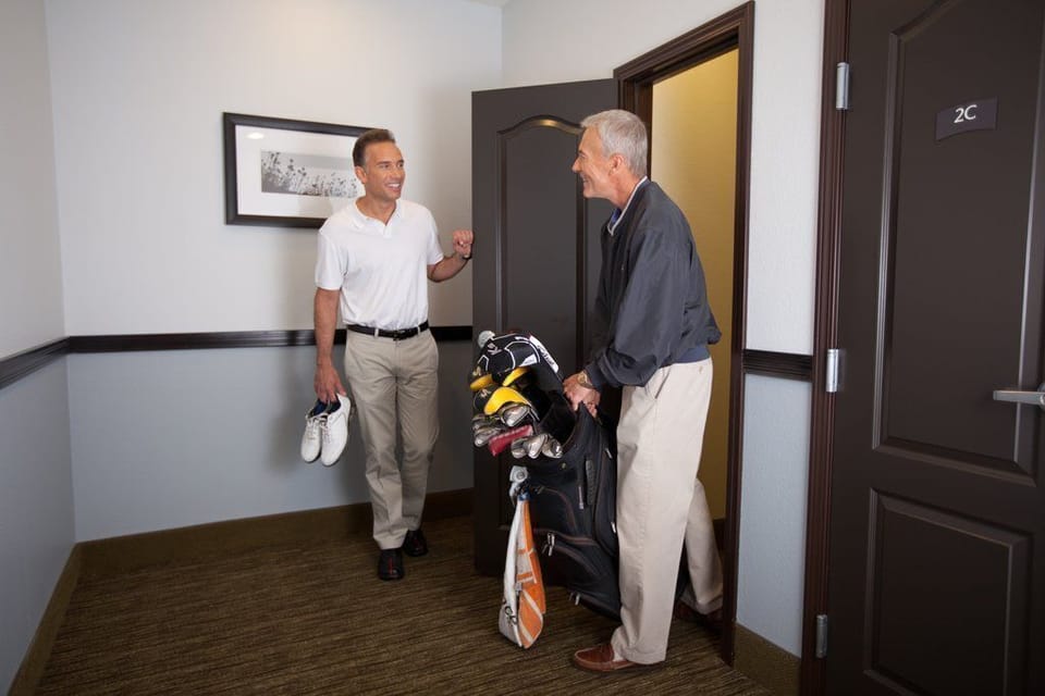 Gear up for a day of golf as friends greet each other just outside the door to a well-appointed room.