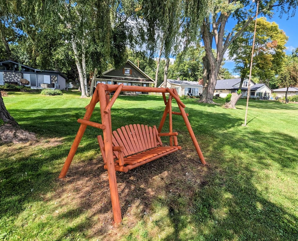 Wooden swing at the edge of the lake in front of the large yard