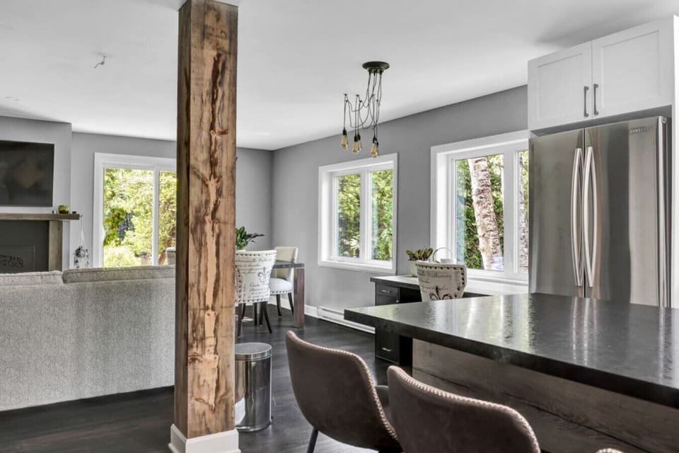 Open-concept kitchen and living area with rustic wood beam accent.