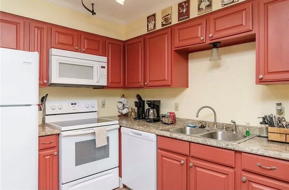 Your fully equipped kitchen awaits with warm coral cabinets, granite countertops, and everything needed to prepare delicious meals during your stay.