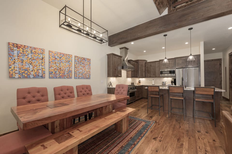 - Long wooden dining table with bench and tufted chairs seats a full group - Overhead chandelier and colorful art add style to every shared meal - Open concept flows into the kitchen for effortless cooking and serving