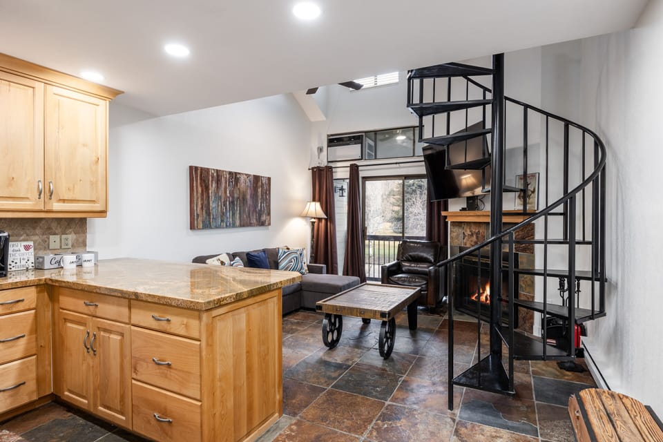 - Open layout with spiral staircase and fireplace glow  
- Cozy living room and kitchen with warm rustic details  
- Perfect Park City condo close to ski slopes and trails