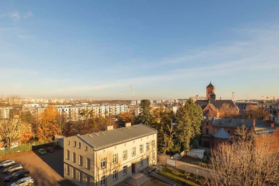 An elevated view of the cityscape, showcasing historical rooftops and a clear sky, visible from the apartment’s windows.

