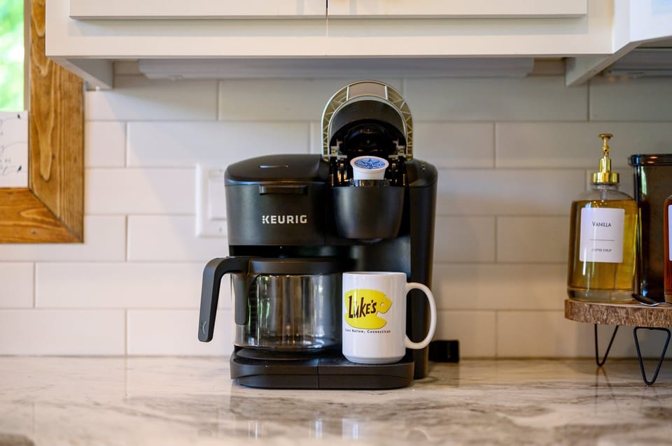 Black Keurig with a latte mug, soap dispenser, and subway tile backsplash.