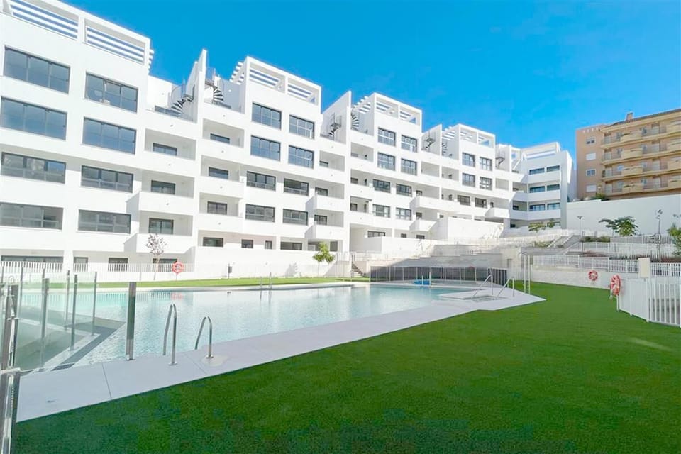 Communal swimming pool surrounded by grass in this complex