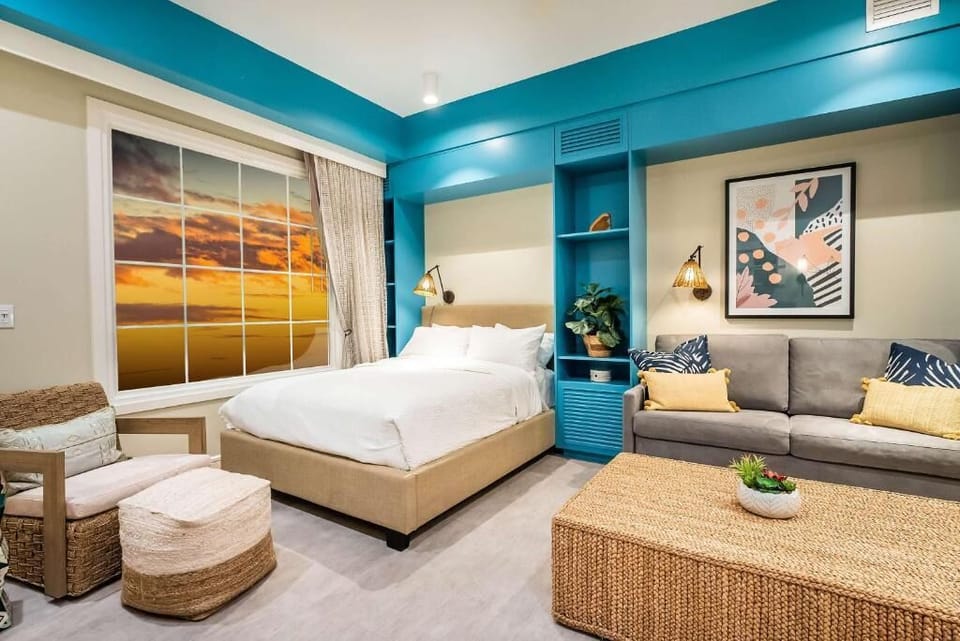 Unwind in a sunlit studio with plush bed and sofa.