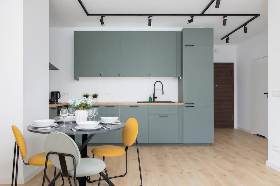 A detailed look at the kitchen area with sleek green cabinets, a built-in oven, and open shelving for a stylish, functional cooking space.

