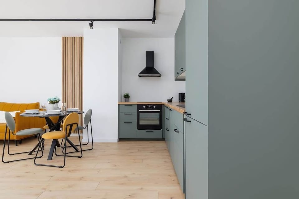 Another angle of the dining area showing mustard yellow chairs paired with a round black table, maintaining a vibrant, cohesive color palette.

