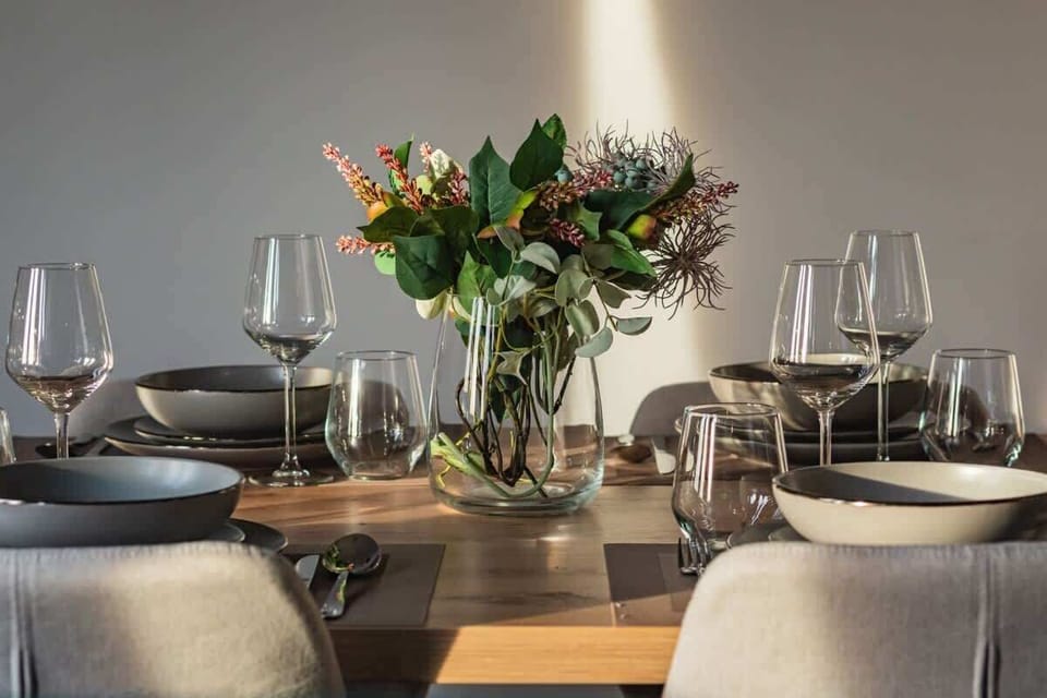 A close-up of a dining table set with elegant glassware and floral centerpiece.

