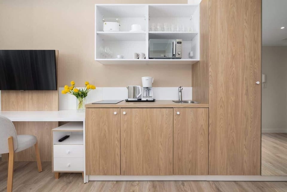A functional kitchen area with open shelves, kettle, and a clean, minimalist design.

