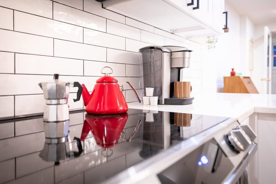 Kitchen with a stove shown with a kettle, Nespresso machine and a coffee maker. 