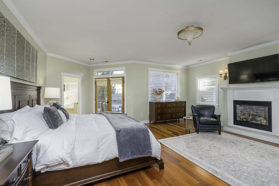A large master bedroom with space for a king bed, a sitting area by the fireplace.