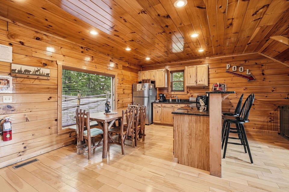 Step into your rustic cabin kitchen and dining area, where warm wood tones create a cozy mountain retreat. Large windows bring nature inside as you prepare meals and gather with loved ones.