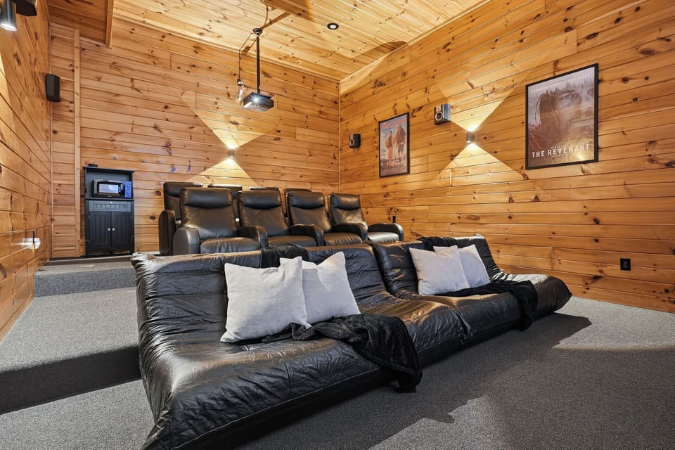 Sink into plush recliners and oversized lounge chairs in your private home theater, where rustic wood walls meet cinematic comfort for unforgettable movie nights.